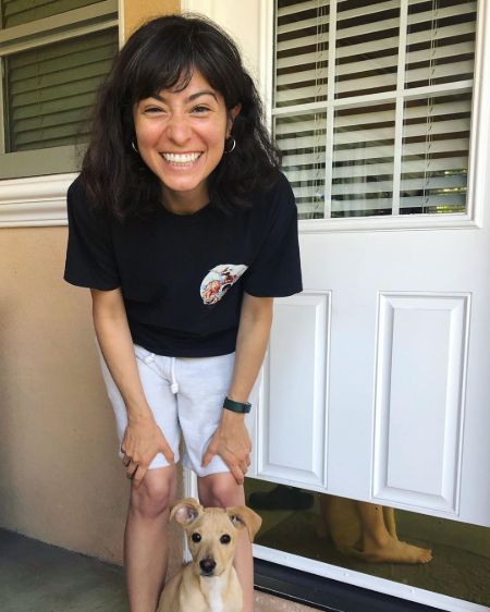 Melissa Villaseñor in a black t-shirt poses with her dog.